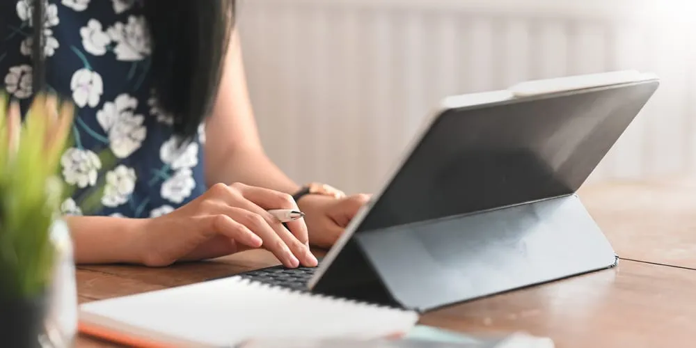 A woman uses an iPad case including a stand and keyboard at her desk.